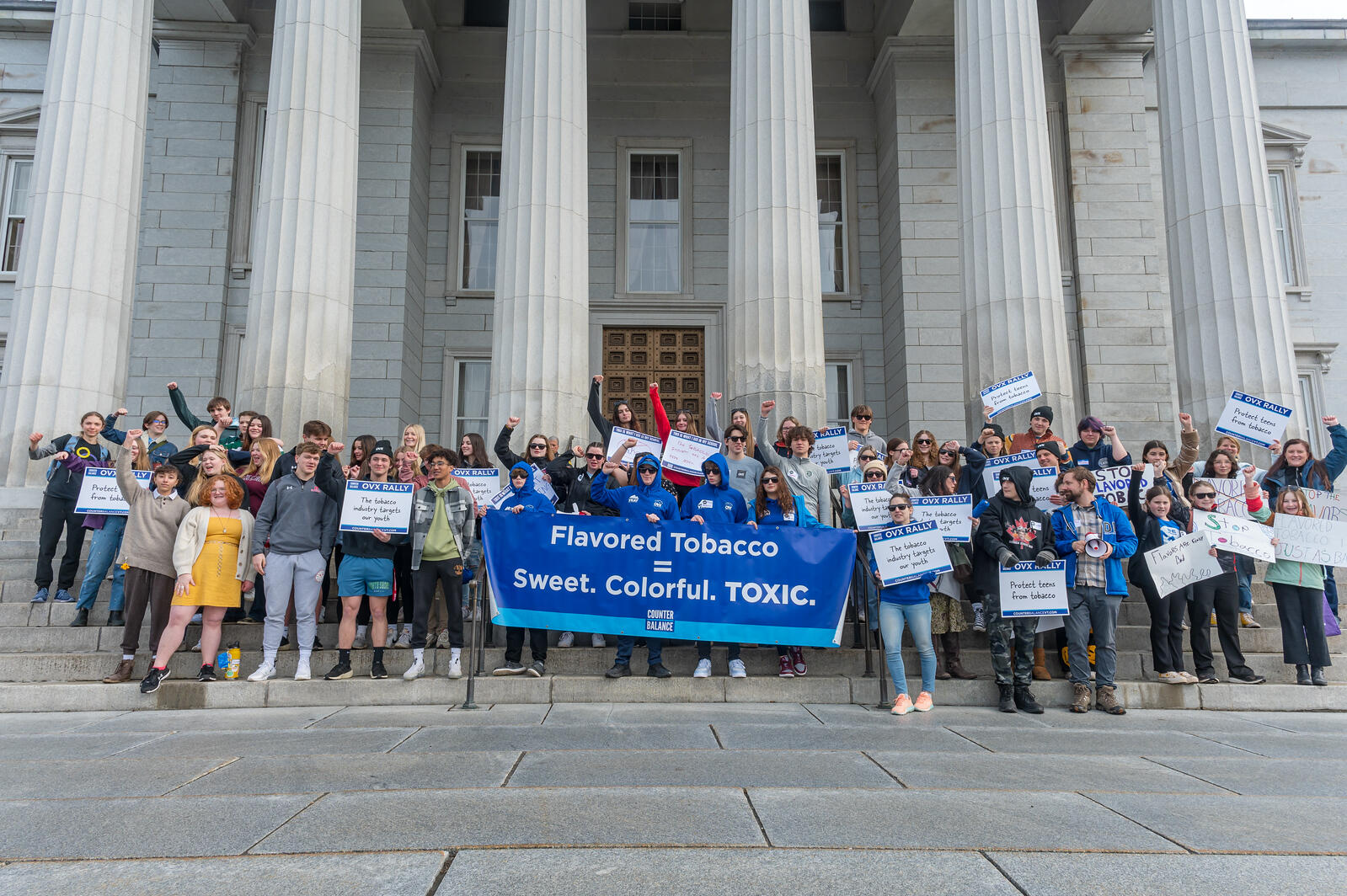 Group of people on the Statehouse steps for OVX rally holding signs about tobacco.