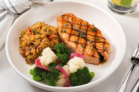 cooked fish with rice and vegetables on a plate