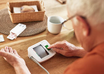 An older man uses a home blood pressure monitor