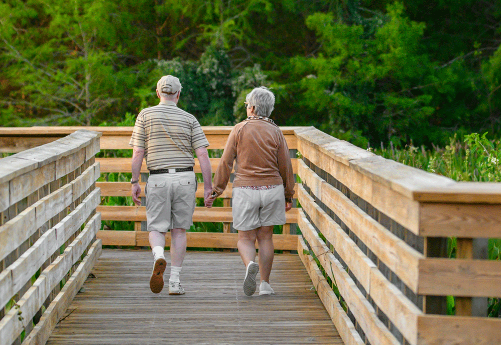 Older couple walking outside down a wooden walkway