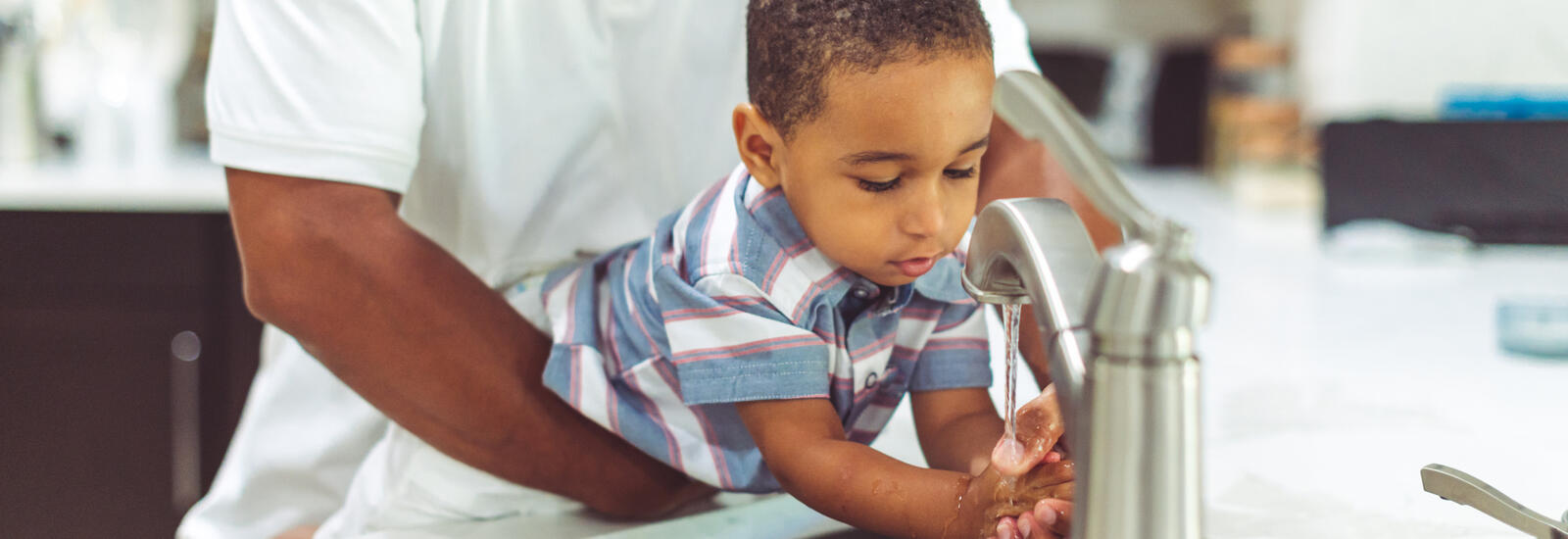 Father helping his child with handwashing.