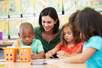 Teacher sitting with 3 small children working at a table