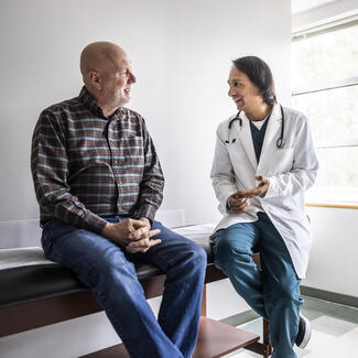 A health care provider sitting next to a man on an exam table