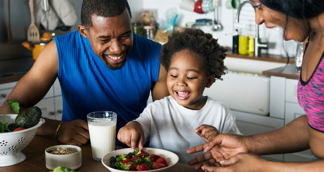 Image of African American family enjoying fresh fruit and vegetables and a glass of milk