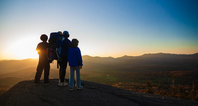 Image of hikers standing on a summit looking out at the landscape